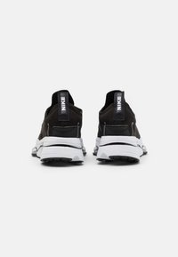 Nike boty, černý semišový svršek, bílá mezipodešev, výrazné zadní poutko, polstrovaný límec, textura podrážky s gripovými vzory.