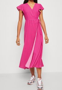 Lyserød slå-om-kjole med korte, flagrende ærmer, prydet med et hjerteprint og bindebånd i taljen. Stoffet ser let og glat ud.