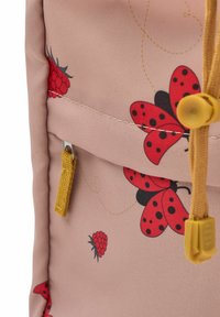 Rosa ryggsäck med röda nyckelpigor och hallonmönster, texturerat tyg, zipficka med gul dragkedja och kontrasterande sömnadsdetaljer.