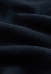 Marineblauer Stoff mit weicher, glatter Textur, der sanfte Falten und ein gleichmäßiges, gleichmäßiges Webmuster aufweist.