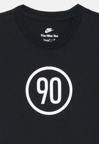 Juodas Nike marškinėliai su apvaliu baltu logotipu, kuriame centre išryškintas skaičius "90". Minkšta medžiaga, apvalios kaklo dizainas.