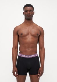 Boxeri negri cu un brâu lila având branding-ul "BJÖRN BORG". Material neted, elastic, cu un design ajustat și cusături vizibile.