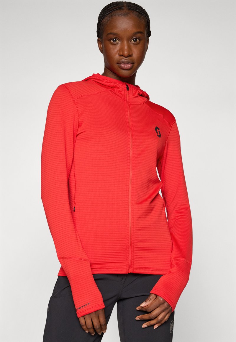 Czerwona bluza z kapturem na zamek błyskawiczny, o strukturalnym wzorze i dopasowanym kroju. Posiada czarne logo na piersi oraz otwory na kciuki w mankietach.