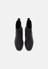 Mustad musta värvi textuurses nahast pahkluu saapad, millel on tõmblukk ja tõmbeava, sile tald ja peened perforatsioonid.