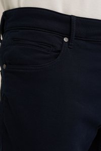 Pantalone od rastezljivog pamuka tamnoplave boje s glatkom teksturom, detaljima prednjih džepova i sjajnim metalnim dugmetom na pojasu.