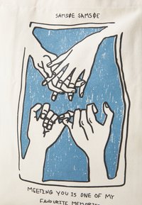 Canvas bag featuring a blue background with a hand-drawn illustration of intertwined hands, paired with text at the bottom.