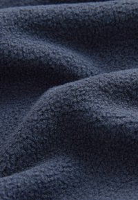 Marinblå fleece-tyg med en mjuk, strukturerad yta och ett subtilt mönster av upphöjda fibrer, vilket ger ett varmt och mysigt utseende.