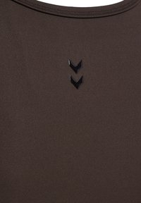 Braunes Trägershirt aus glattem, dehnbarem Stoff. Auffällige schwarze Chevron-Grafik nahe dem Ausschnitt sorgt für visuelles Interesse.