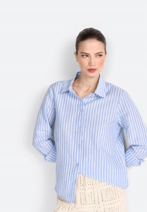 Chemise boutonnée rayée bleu clair et blanche avec manches longues, dotée d'un col classique et d'un ourlet légèrement asymétrique.