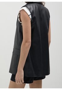 Svart läderväst utan ärmar med skräddarsydd passform, med krage och fickor. Designen har en jämn textur och en ren silhuett.