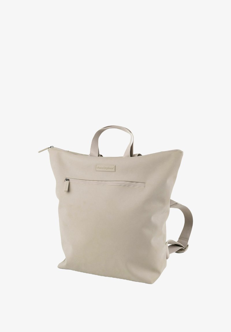 Rucsac bej deschis, fabricat dintr-un material neted. Dispune de o închidere cu fermoar, un buzunar frontal cu fermoar și bretele ajustabile. Design minimalist.