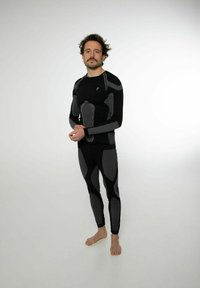 Schwarz aktive Bekleidungset mit eng anliegenden langen Ärmeln und Leggings, mit grauen Details und gestreiften Mustern, hergestellt aus strukturiertem, flexiblem Material.