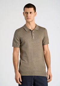 Polo de manga corta en marrón con tejido texturizado, que presenta un cuello, tres botones y un pequeño logotipo en el pecho.