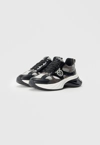 Zwarte en grijze sneakers met een glanzende afwerking, voorzien van een gestructureerd design, dikke witte zool en een logo-accent aan de zijkant.