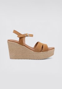Sandalia wedge de ante en tono marrón con tres tiras frontales y una tira en el tobillo. Plataforma envuelta en yute con un acabado texturizado. Hebilla metálica ajustable.