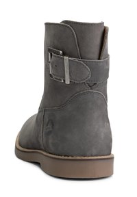 Šedá kožená kotníková bota s kulatou špičkou, bočním detaily s přezkou a nízkou béžovou podrážkou. Jemná textura na povrchu kůže.