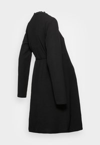 Robe noire à manches longues avec un tissu texturé, un col rond et une ceinture à nouer à la taille. Finition en dentelle unique au col.