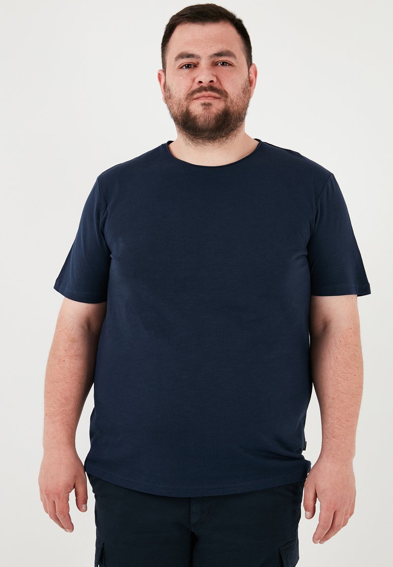 Tricou cu mânecă scurtă de culoare albastru marin, fabricat dintr-un material de bumbac neted. Are un decolteu rotund și o siluetă relaxată.