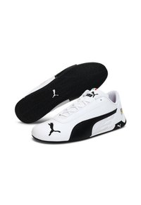 Chaussures de course Puma blanches et noires au design épuré, tige synthétique, semelle texturée et logos bien visibles sur les côtés et le bout.