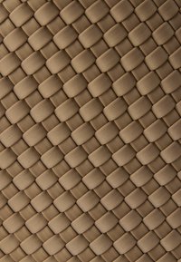 Υφαντό υλικό σε μπεζ τόνο, με σχέδιο που παραπέμπει σε πλέγμα με στρογγυλεμένες, ανυψωμένες περιοχές, δημιουργώντας μια υφασμάτινη επιφάνεια.