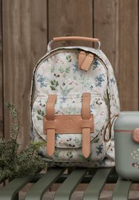 Ryggsäck med blommönster på en ljus krämfärgad bas, beige läderdetaljer, justerbara remmar och ett handtag upptill, kombinerad med en mintgrön lunchlåda.
