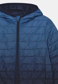 Veste matelassée bleu marine avec capuche, dotée d'un zip à l'avant et d'une texture matelassée. Matériau lisse et léger avec un design épuré.
