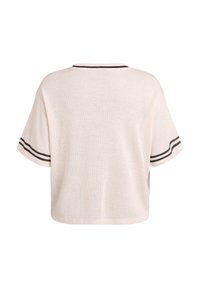 Top de manga corta color crema con un ajuste holgado, que presenta un cuello redondeado y detalles de rayas negras en las mangas. Tejido de punto texturizado.