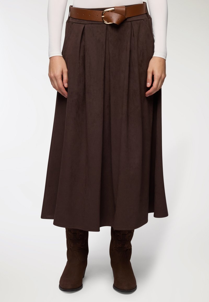 Gonna plissettata marrone realizzata in tessuto morbido, abbinata a una cintura larga marrone con fibbia metallica e stivali marroni al ginocchio con motivi.