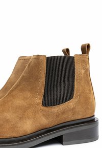 Brown suede ankle boots featuring a black corduroy panel, elastic side, and a low, flat black heel. Clean lines and simple design.