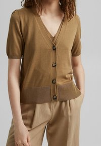 Brun kortärmad cardigan med V-ringning, fem knappar och ribbad nederkant. Mjukt, stickat material med en något texturerad yta.