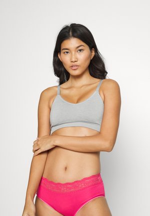 Grauer Baumwoll-Bralette mit verstellbaren Trägern und rundem Ausschnitt. Kombiniert mit rosa Unterwäsche, die eine Spitzenkante an der Taille betont.