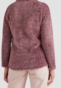 Futrzasty, długosleeve pulower w stonowanym odcieniu różu. Miękka faktura i luźny krój. Posiada wysoki kołnierz i zaokrąglony dół.