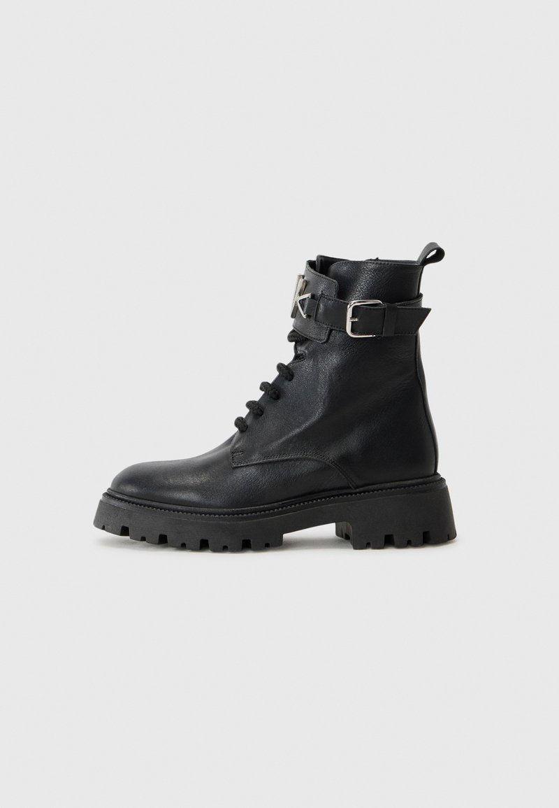 Stivaletti in pelle nera con punta tonda, lace-up frontale e fibbia laterale. Suola testurizzata con scanalature profonde per una buona aderenza.