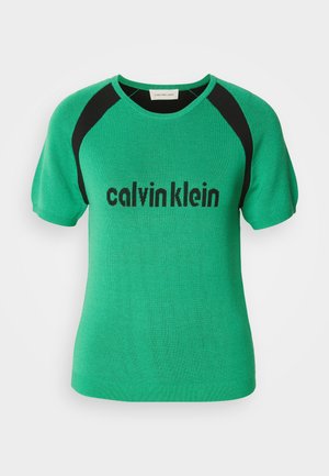 Groene gebreide top met korte mouwen, voorzien van zwarte accenten op de schouders en het "calvinklein" logo in het zwart over de voorkant. Gladde textuur.