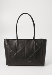 Zwarte lederen tote bag met gegraveerde geometrische patronen, uitgerust met twee lange handvaten en een merklogo aan de onderkant. Ruimtelijk ontwerp.