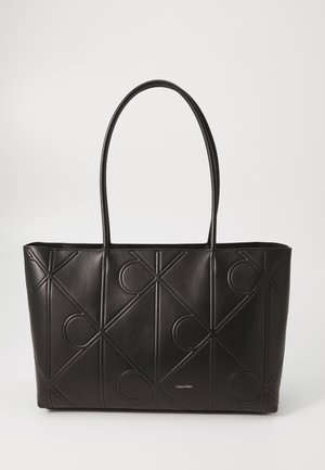 Bolso tote negro de cuero con patrones geométricos en relieve, que cuenta con dos asas largas y un logo de la marca en la parte inferior. Diseño espacioso.
