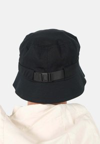 Czarny kapelusz typu bucket z prążkowaną teksturą, szerokim rondem i regulowanym paskiem z tkaniny z tyłu. Prosty design, odpowiedni na codzienne noszenie.