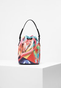 Borsa a secchiello colorata con pennellate astratte e una maniglia in pelle nera esposta su un piedistallo bianco contro uno sfondo semplice.
