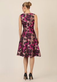 Blumenkleid in Schwarz mit lebhaften pinken und lila Mustern. A-Linie Silhouette, ärmellos, knielang, mit verdecktem Rückenreißverschluss.