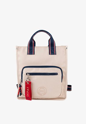 Bolso tote de tela beige con detalles en azul oscuro, un bolsillo frontal con cremallera, asas superiores y una etiqueta roja desmontable. Cuenta con un detalle de logo circular.