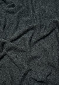 Tissu gris foncé doux présentant une surface texturée et légèrement pelucheuse avec une apparence drapée, mettant en valeur de légers plis et rides.