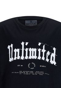 Schwarzes Baumwoll-T-Shirt mit auffälligem, weißem Gothic-Schriftzug, der "Unlimited" liest, sowie zusätzlichem kleinerem Text darunter. Runder Halsausschnitt.
