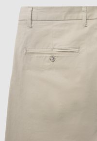 Pantaloni beige con una texture liscia, una vita con passanti per cintura e una tasca posteriore chiusa con un bottone.