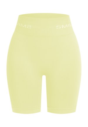 Shorts de vélo taille haute jaune clair, en matériau lisse et extensible. Avec le texte blanc "SMILE" le long de la taille.