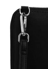 Black leather crossbody bag corner with zipper, featuring a silver metal clasp and strap attachment. Smooth texture, minimalist design details.