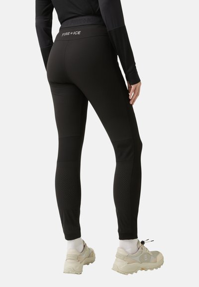 Black athletic leggings with a high waistband, featuring textured panels and perforations at the lower legs. Worn with light-colored sneakers.