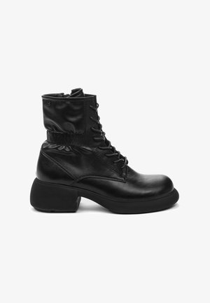 Botas de cuero negras hasta el tobillo con punta redonda, cordones en la parte delantera y un puño texturizado. El tacón grueso aporta estabilidad y una silueta distintiva.
