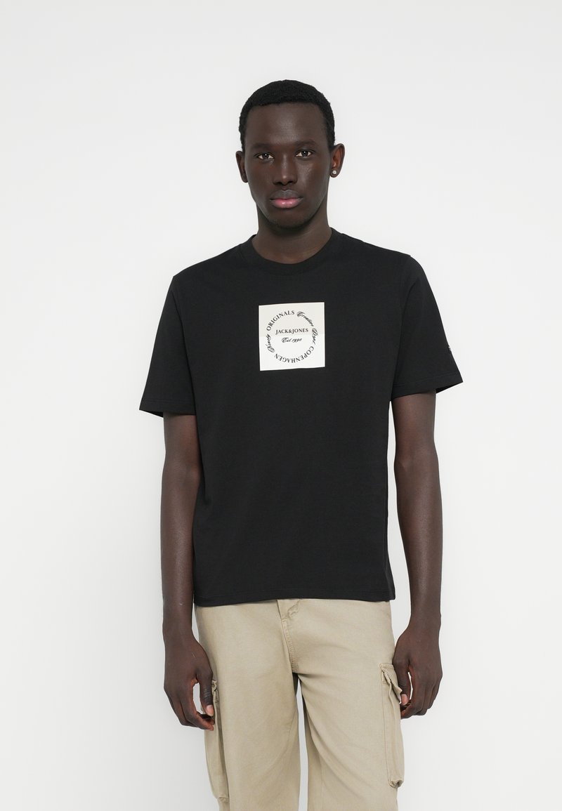 Μαύρο βαμβακερό μπλουζάκι με στρογγυλή λαιμόκοψη και κοντά μανίκια, που διαθέτει κρεμέ λογότυπο στο στήθος. Απλός σχεδιασμός και εφαρμογή.