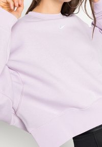 Lavendel Nike sweatshirt med rund hals, oversize passform och ribbade ärmar. Har en vit logotyp på bröstet och en mjuk textur.