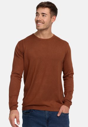 Brauner langärmeliger Baumwollpullover mit rundem Halsauschnitt und gerippten Bündchen, kombiniert mit blauen Jeans.